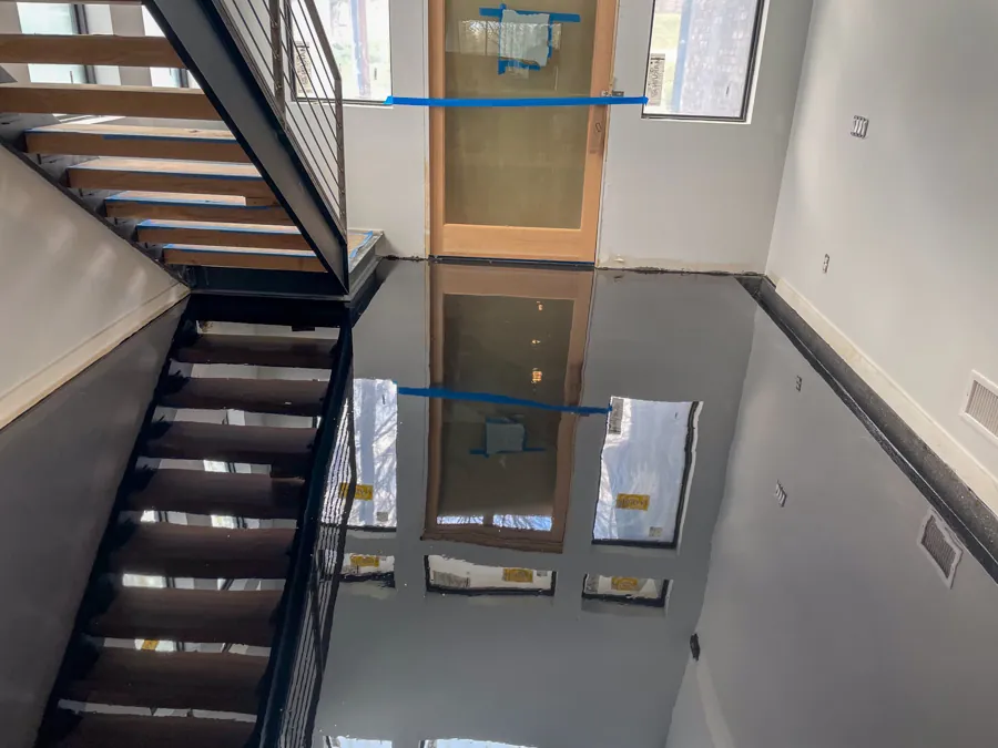 Glossy black epoxy entry floor by a staircase, concrete coating serving Nashville, TN